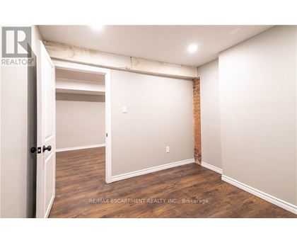 A room with a doorway leading to another room and a brick wall on the side.