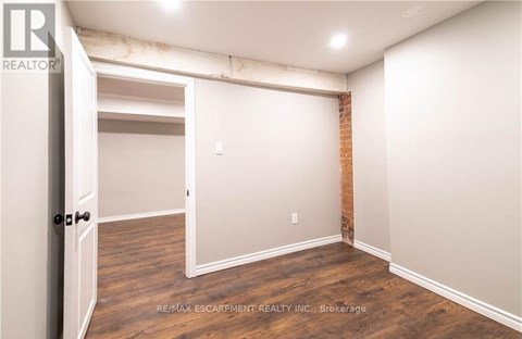 A room with a doorway leading to another room and a brick wall on the side.