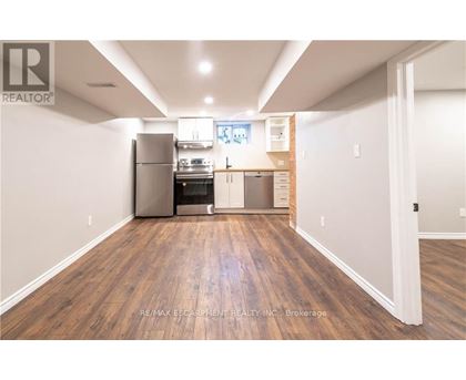 A kitchen with wood flooring and a refrigerator, oven, and microwave.
