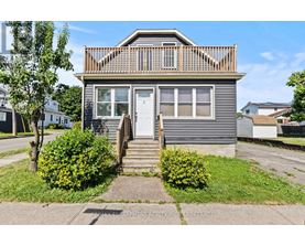 A house with a grey facade and a white door is for sale.
