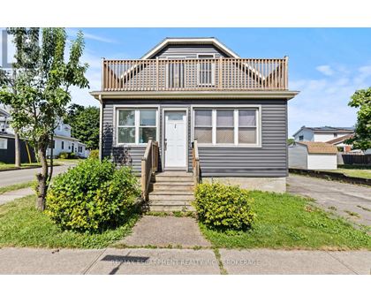 A house with a grey facade and a white door is for sale.