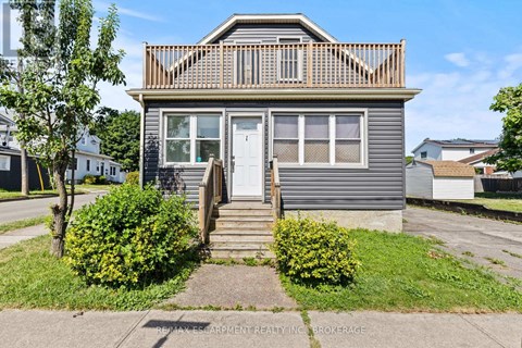 A house with a grey facade and a white door is for sale.