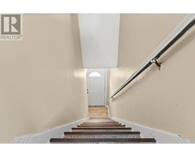 A hallway with a white door at the end and a sign that says RE/MAX Escarpment Realty, Brokerage.