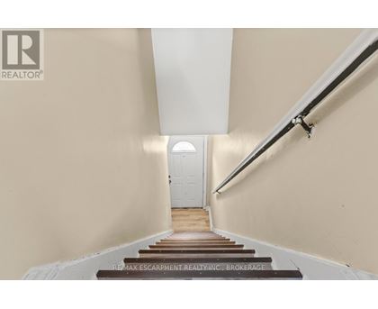 A hallway with a white door at the end and a sign that says RE/MAX Escarpment Realty, Brokerage.