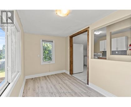 A room with a white door and a window with a view of trees.