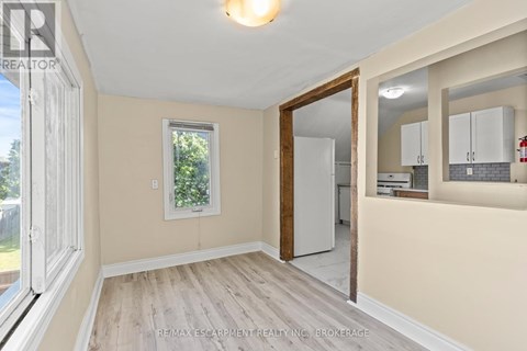 A room with a white door and a window with a view of trees.
