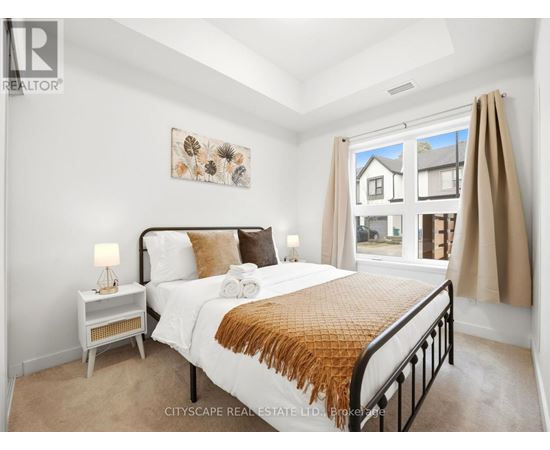 A bedroom with a large bed and a window overlooking a house.