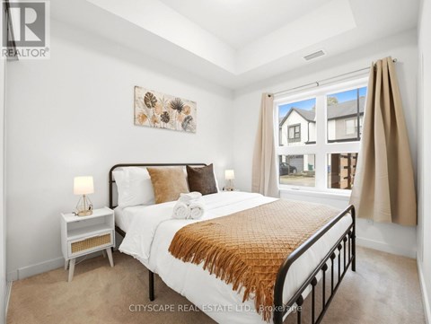A bedroom with a large bed and a window overlooking a house.