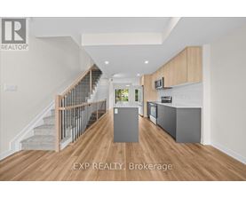 A spacious room with wooden floors and a staircase with a metal railing.