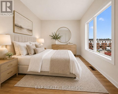 A bedroom with a large bed, a nightstand with a lamp, and a framed picture on the wall.