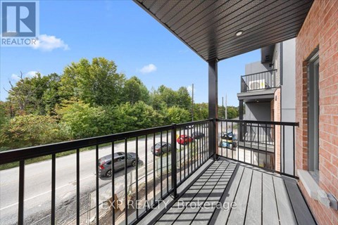 A balcony with a black railing overlooks a street with cars and buildings.