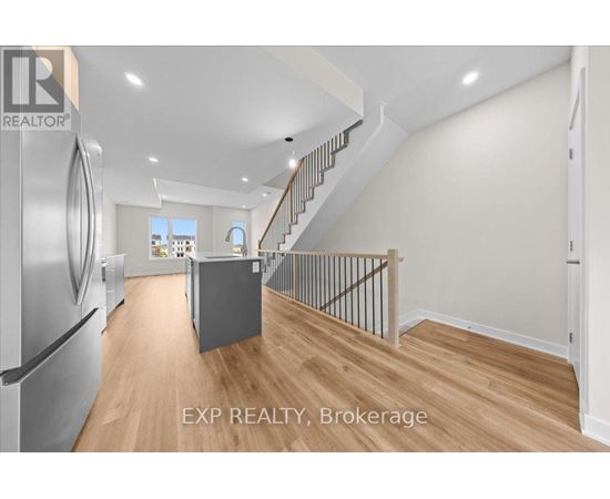 A kitchen with a refrigerator and a staircase.