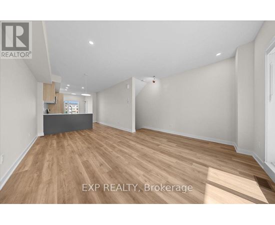 A room with wooden flooring and white walls, with a desk in the corner.