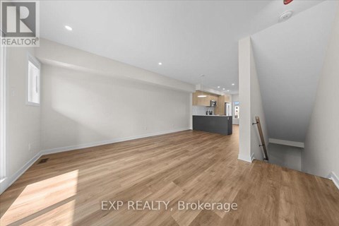 A room with wooden flooring and white walls, with a brokerage logo on the top left.