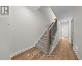 A hallway with a staircase and a door on the right.
