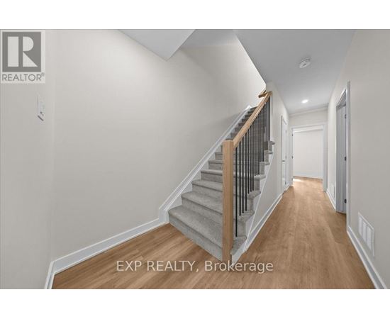 A hallway with a staircase and a door on the right.