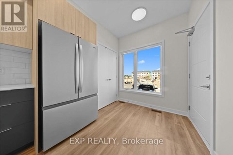 A kitchen with a refrigerator and a window showing a view of a building.