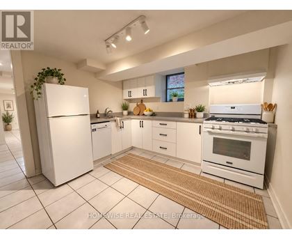 A white kitchen with a refrigerator, oven, and sink.