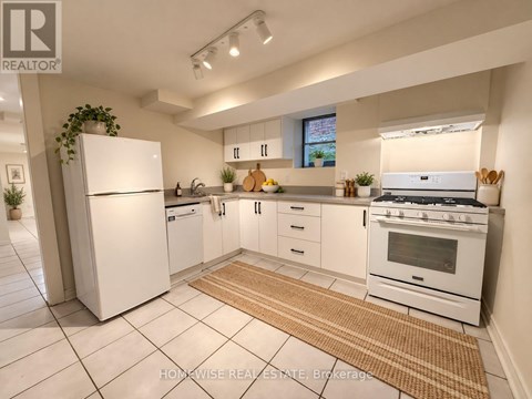 A white kitchen with a refrigerator, oven, and sink.