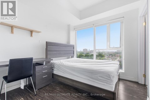 A bedroom with a bed, chair, and window.