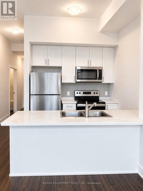 A white kitchen with a stainless steel refrigerator and microwave above the stove.