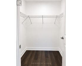 A white closet with a wooden floor and a metal rack.