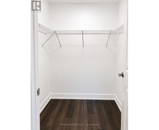 A white closet with a wooden floor and a metal rack.