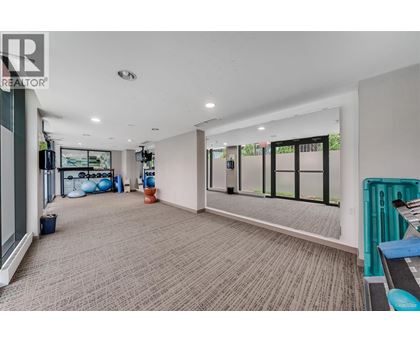 A spacious room with a carpeted floor and large windows.