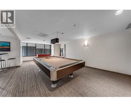 A pool table in a room with a Realtor logo on the wall.