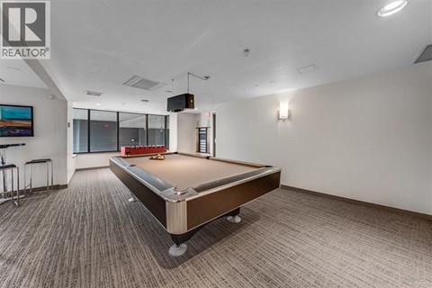 A pool table in a room with a Realtor logo on the wall.