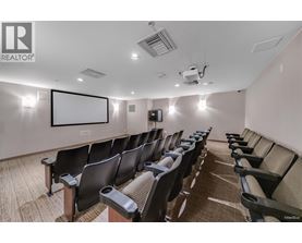 A row of black chairs are arranged in a room with a white screen at the front.