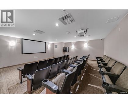 A row of black chairs are arranged in a room with a white screen at the front.