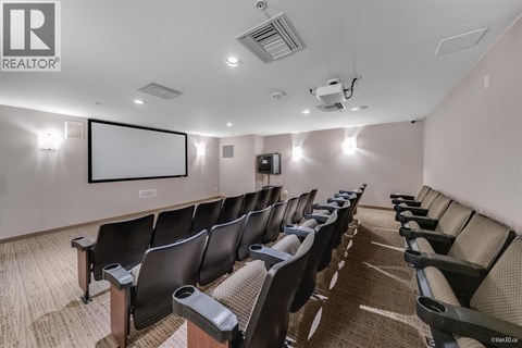 A row of black chairs are arranged in a room with a white screen at the front.