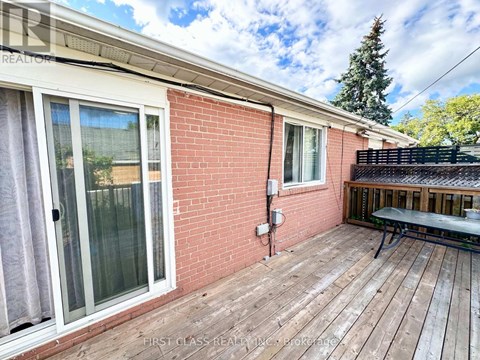 A red brick house with a wooden deck and a glass door.