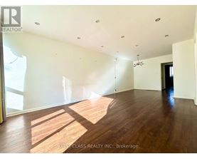 A large empty room with wooden floors and a ceiling fan.