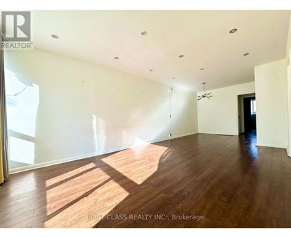 A large empty room with wooden floors and a ceiling fan.