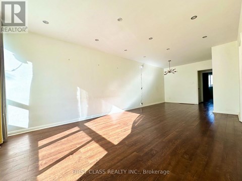 A large empty room with wooden floors and a ceiling fan.