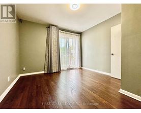 A room with wooden flooring and a window with curtains.