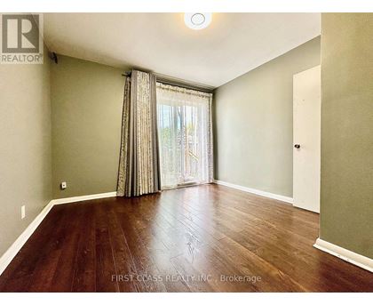 A room with wooden flooring and a window with curtains.