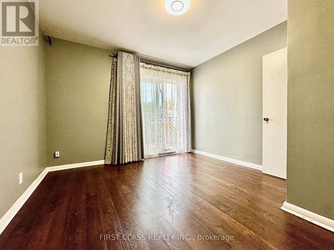 A room with wooden flooring and a window with curtains.