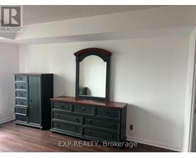 A large mirror sits on a dresser in a room with EXP Realty, Brokerage written on the bottom.