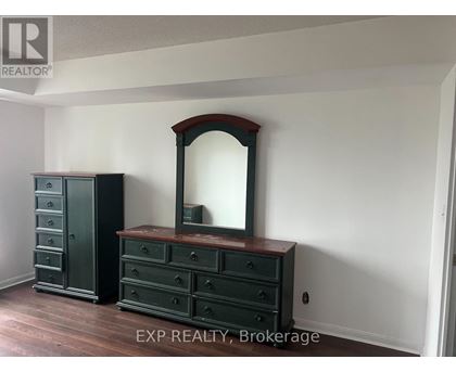 A large mirror sits on a dresser in a room with EXP Realty, Brokerage written on the bottom.