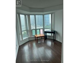 A room with a desk and a chair in front of a window with a view of a city.