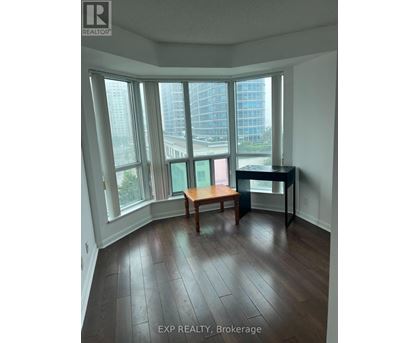 A room with a desk and a chair in front of a window with a view of a city.