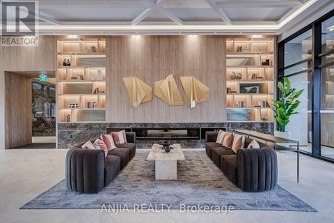 A modern living room with a long black couch and a coffee table in the center.