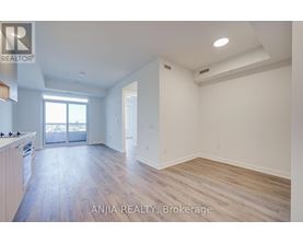 A spacious room with wood flooring and white walls.