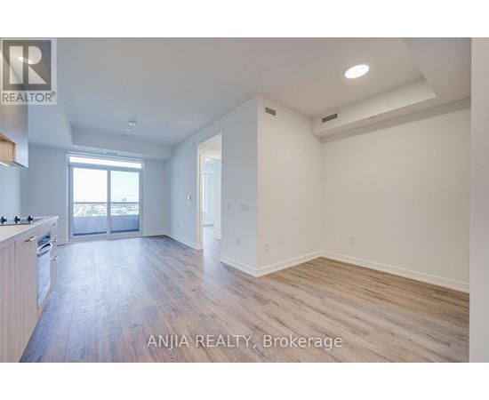 A spacious room with wood flooring and white walls.