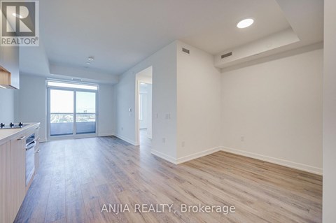 A spacious room with wood flooring and white walls.