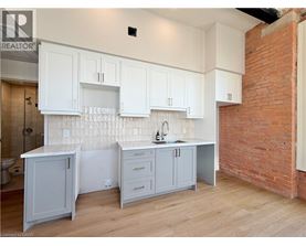 A kitchen with white cabinets and a brick wall.
