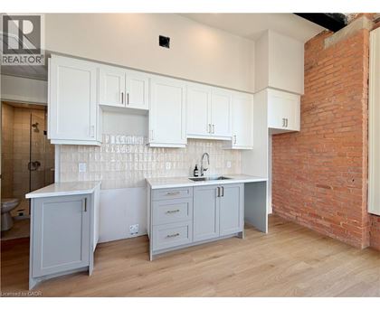 A kitchen with white cabinets and a brick wall.